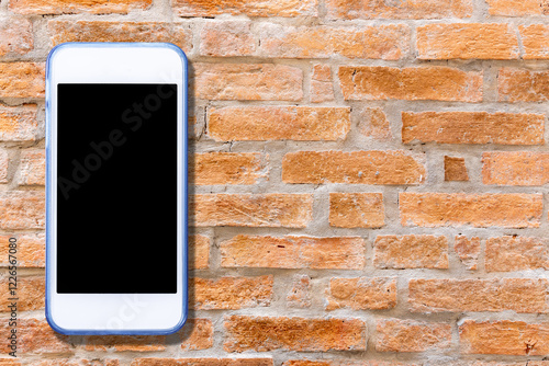 A vintage mobile phone rests against a textured brick wall, its blank screen reflecting the light filtering through an old window photo