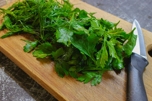 Obraz na płótnie Chopped greenery on wooden board. Bunch of dill and parsley on cutting board with knife. Vegan diet concept. Healthy food. Fresh herbs on wooden chopping board. w salonie
