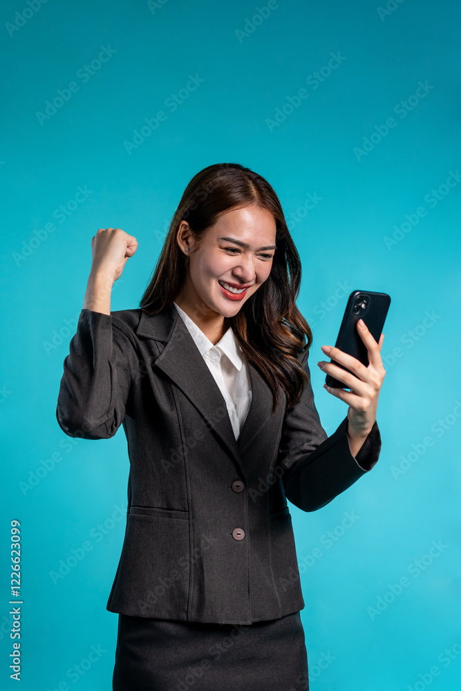 Asian excited woman looking at mobile phone in isolated blue background. Asian excited woman looking at mobile phone in isolated blue background.