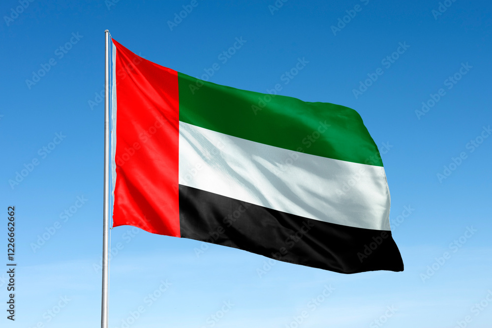 Waving United Arab Emirates, UAE flag, national symbol, blue sky Waving United Arab Emirates, UAE flag, national symbol, blue sky