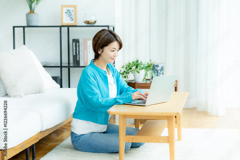 自宅でノートパソコンを操作する若い女性 自宅でノートパソコンを操作する若い女性