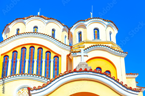 Obraz na płótnie Domes of Shkoder Orthodox Cathedral in Albania. View of a beautiful yellow and white church with multiple domes, arched windows, and a cross on the roof, all set against a clear blue sky w salonie