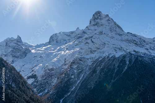 Snow-capped peaks with majestic blue slopes rise above rugged slopes of North Caucasus mountain range. Picturesque pine and spruce forests grow at foot of mountains with eternal glaciers. Dombai. photo