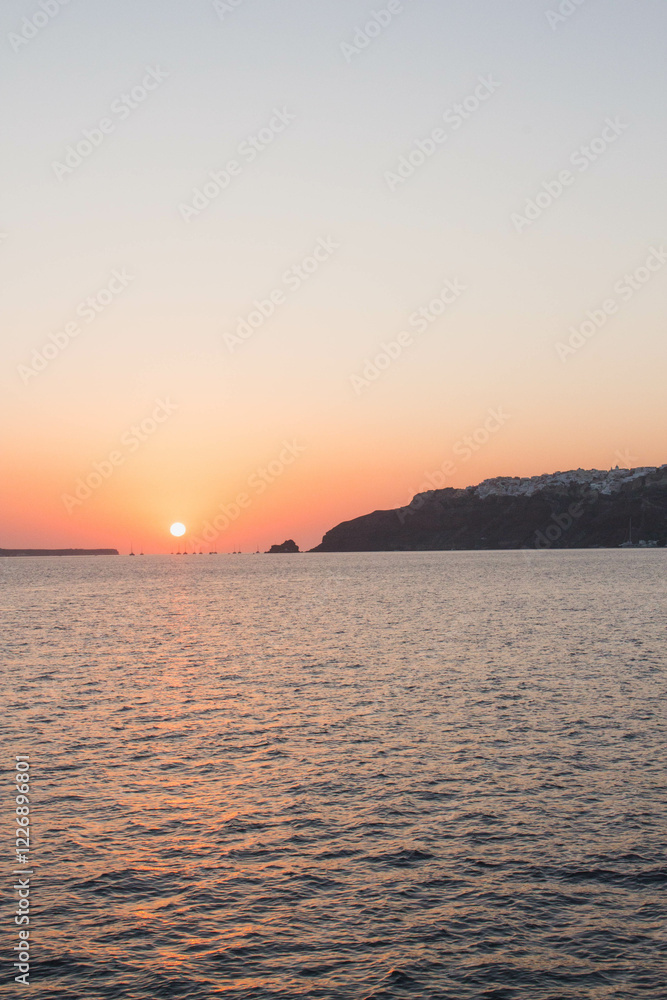 Island sunset on water in the Aegean Sea in Santorini, Greece Island sunset on water in the Aegean Sea in Santorini, Greece