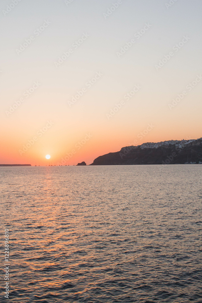 Island sunset on water in the Aegean Sea in Santorini, Greece Island sunset on water in the Aegean Sea in Santorini, Greece