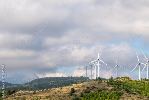 Wind turbines rise over the rural landscape of Navarra, Spain, generating clean, renewable energy. The misty morning enhances the atmospheric scene, symbolizing sustainability and future photo