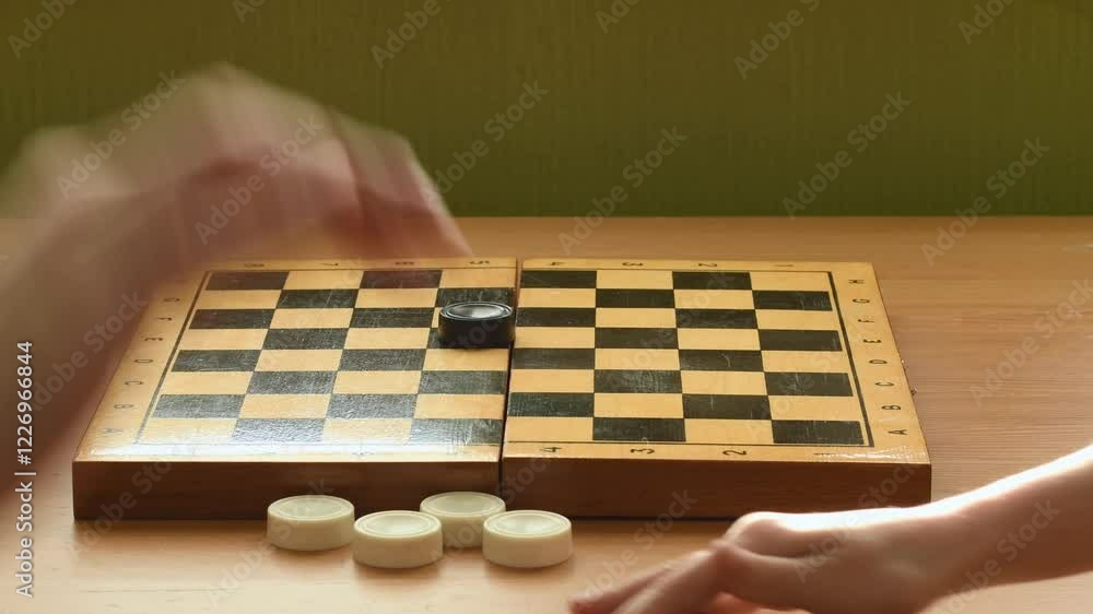 Angry after losing, the girl sweeps checkers off the board. Frustration, exhaustion, nerves, emotions, family game. Angry after losing, the girl sweeps checkers off the board. Frustration, exhaustion, nerves, emotions, family game.