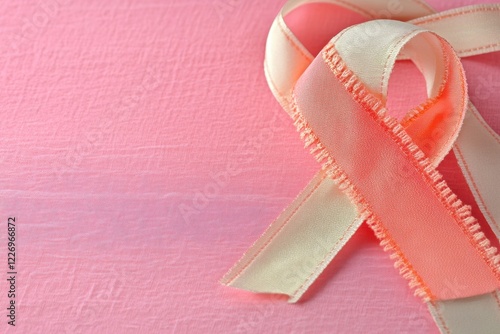 Pink coral ribbon awareness symbol on pink textured background photo