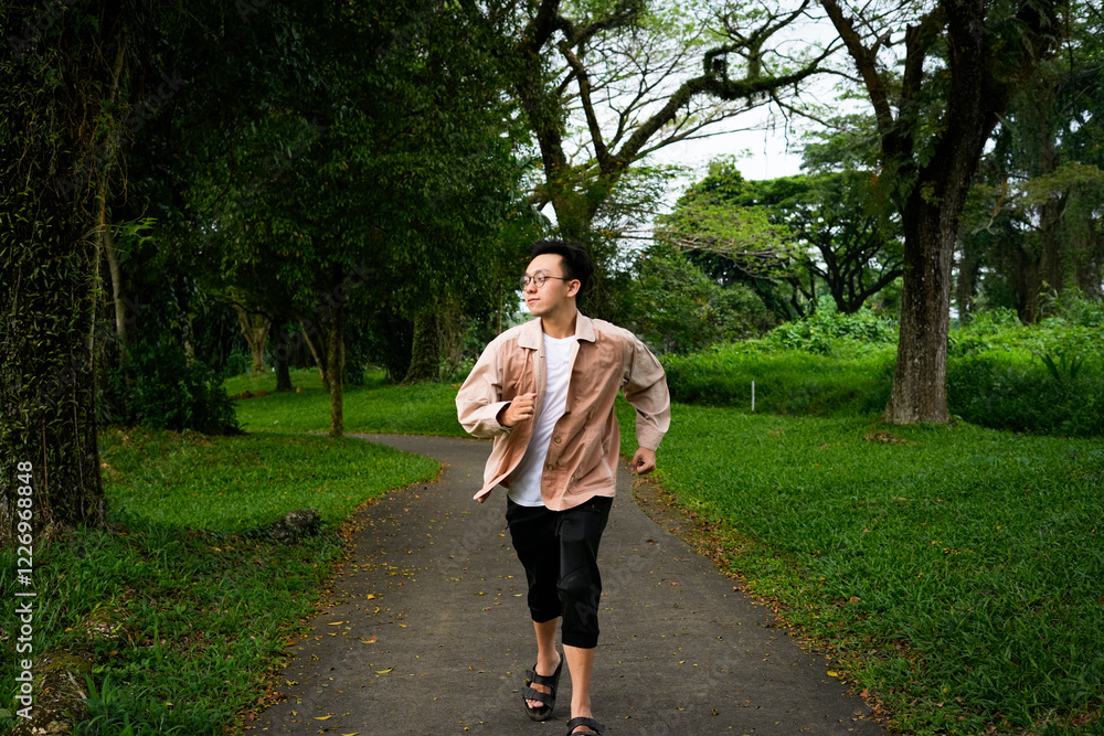 Fototapeta premium Man Jogging Along a Curved Path in a Peaceful Green Park