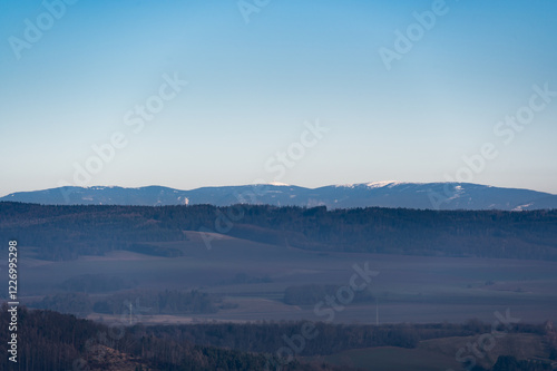 Obraz na płótnie Distant view of the Jeseniky Mountains with Praded peak rising above the horizon. The vast landscape showcases rolling hills, deep forests, and the beauty of Czech nature w salonie