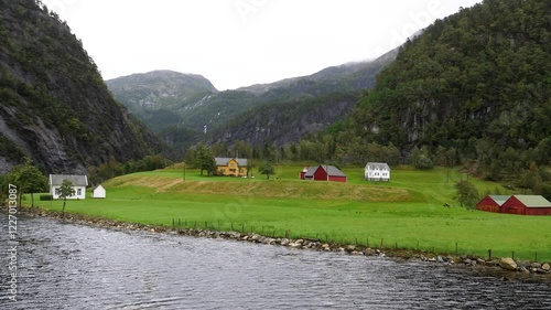 Beautiful Norwegian village on the shore of Mostraumen fjord, view from passing cruise boat. photo