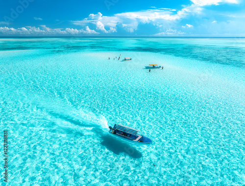 Fototapeta Naklejka Na Ścianę i Meble -  Aerial view of floating boat in transparent azure water on sunny summer day. Mnemba island, Zanzibar. Top view of yacht, sandbank in low tide, clear blue sea, sand, sky with clouds. Motorboat in ocean