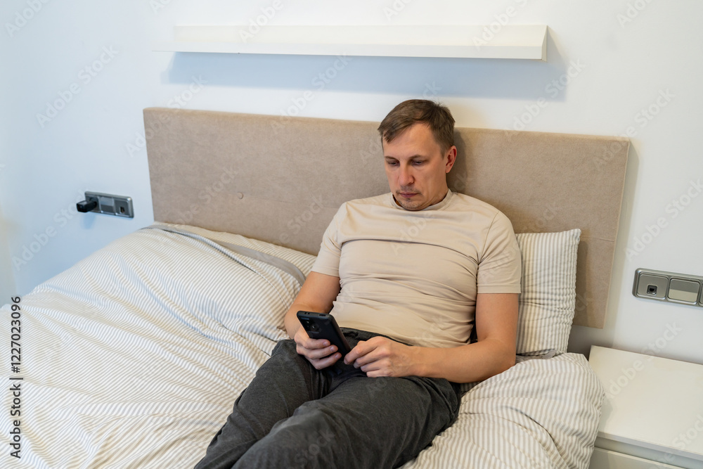 man lying in bed while watching on phone. man lying in bed while watching on phone.