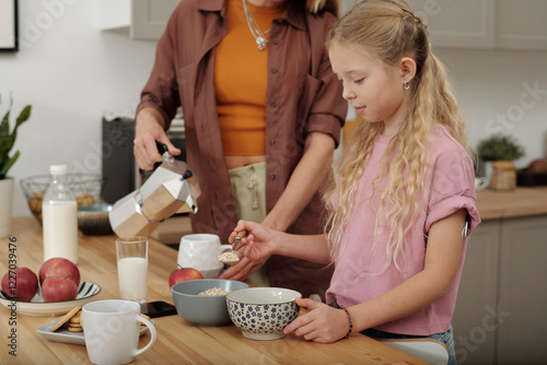 Portrait of cute young girl making healthy breakfast with oats in cozy kitchen enjoying morning with mother at home copy space  photo