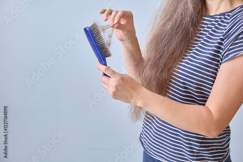 Faceless woman cleans her comb after copious hair loss. Copy space photo