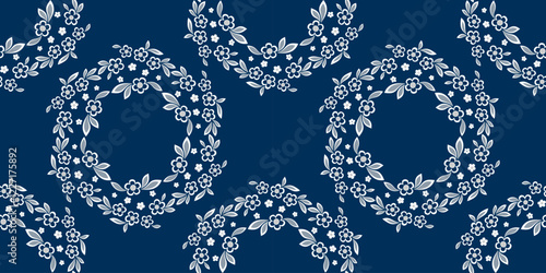 Seamless pattern of round floral element. White flowers on dark blue background. Wreath of flowers and leaves in country style. Romantic graceful floral vector ornament. Vintage delicate embroidery