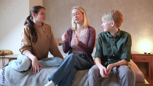 
A mother sits with her children in the bedroom, discussing home rules and their behavior. She explains expectations while they listen and share their thoughts.