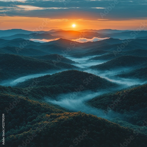 Sunset casting a beautiful glow among the mountains, with orange clouds framing the sun