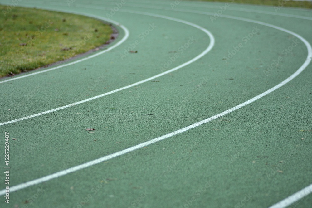 Green running track curve with white lines and green grass in the sides. Green running track curve with white lines and green grass in the sides.