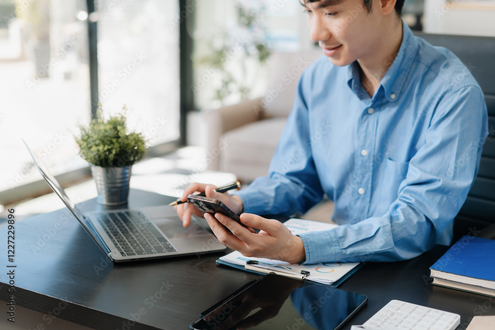 pleasant looking successful professional male business accountant learns clients case, works on modern laptop and smartphone. pleasant looking successful professional male business accountant learns clients case, works on modern laptop and smartphone.