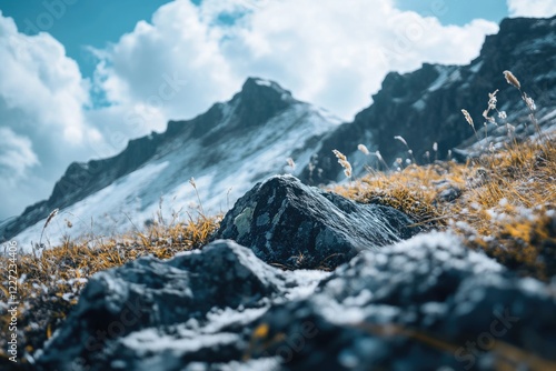 A rock sits on a snowy mountain. The sky is cloudy and the mountain range is in the background