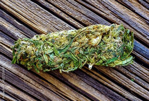 Macro detail of single cannabis bud (mangolope marijuana strain) over wooden dark background