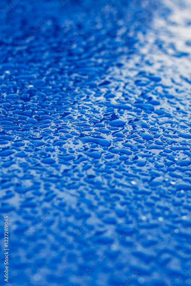 A detailed close up of water drops resting on a blue surface A detailed close up of water drops resting on a blue surface