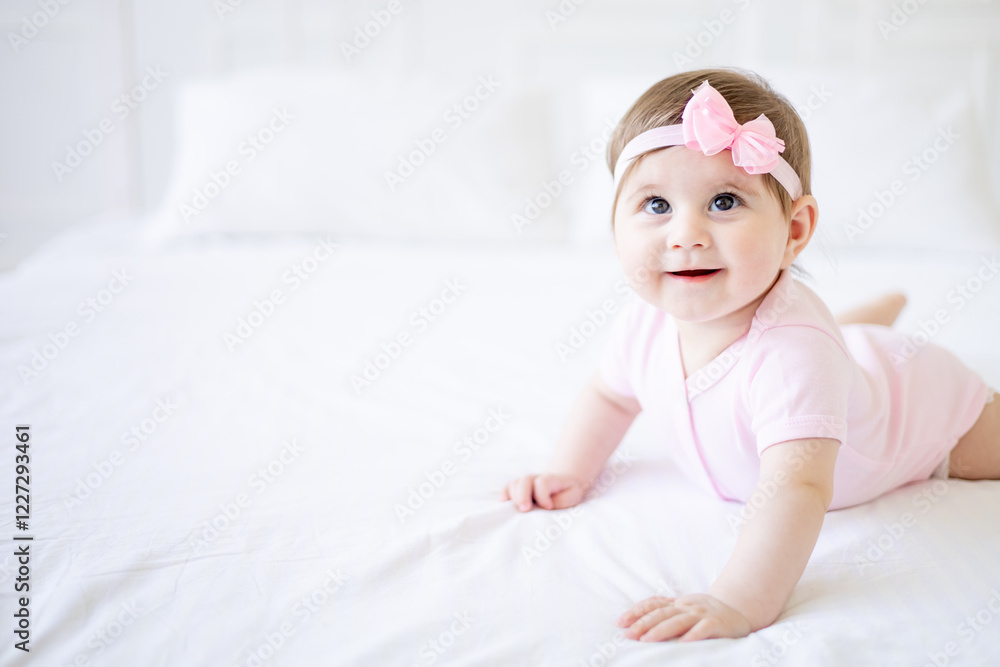 a six-month-old baby learns to crawl on a white cotton bed at home, a cute little baby girl in a pink bodysuit smiles and rejoices, close-up a six-month-old baby learns to crawl on a white cotton bed at home, a cute little baby girl in a pink bodysuit smiles and rejoices, close-up