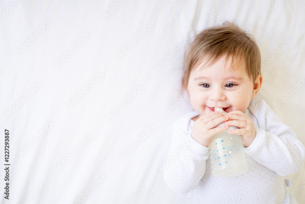 baby sucking a bottle of milk on a white cotton bed at home, cute little baby girl eating milk, baby food concept, close-up portrait baby sucking a bottle of milk on a white cotton bed at home, cute little baby girl eating milk, baby food concept, close-up portrait