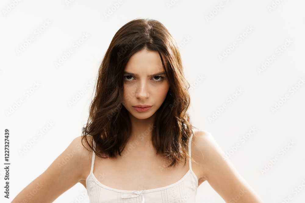 Young brunette woman in a white light top posing against a white background, expressing emotions and touching her face with her hands. Minimalistic and natural beauty concept Young brunette woman in a white light top posing against a white background, expressing emotions and touching her face with her hands. Minimalistic and natural beauty concept