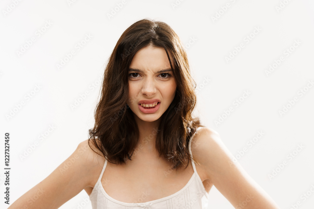 Young brunette woman in a white light top posing against a white background, expressing emotions and touching her face with her hands. Minimalistic and natural beauty concept Young brunette woman in a white light top posing against a white background, expressing emotions and touching her face with her hands. Minimalistic and natural beauty concept