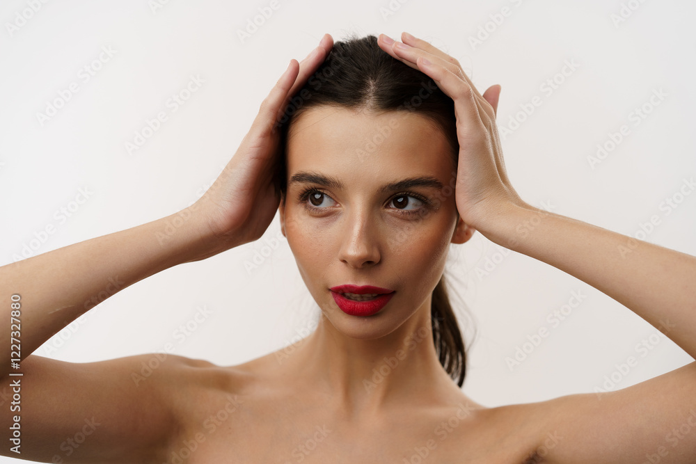 Young brunette woman with red lipstick posing against a white background, expressing emotions, and touching her face with her hands. Minimalistic beauty and fashion concept Young brunette woman with red lipstick posing against a white background, expressing emotions, and touching her face with her hands. Minimalistic beauty and fashion concept