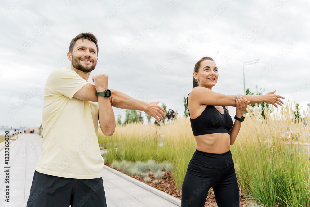 Two individuals stretching together in a park on a cloudy day Two individuals stretching together in a park on a cloudy day