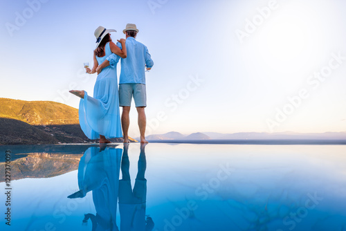 Obraz na płótnie A elegant summer vacation or honeymoon couple enjoys the mediterranean sunset with a glass of wine by the pool w salonie
