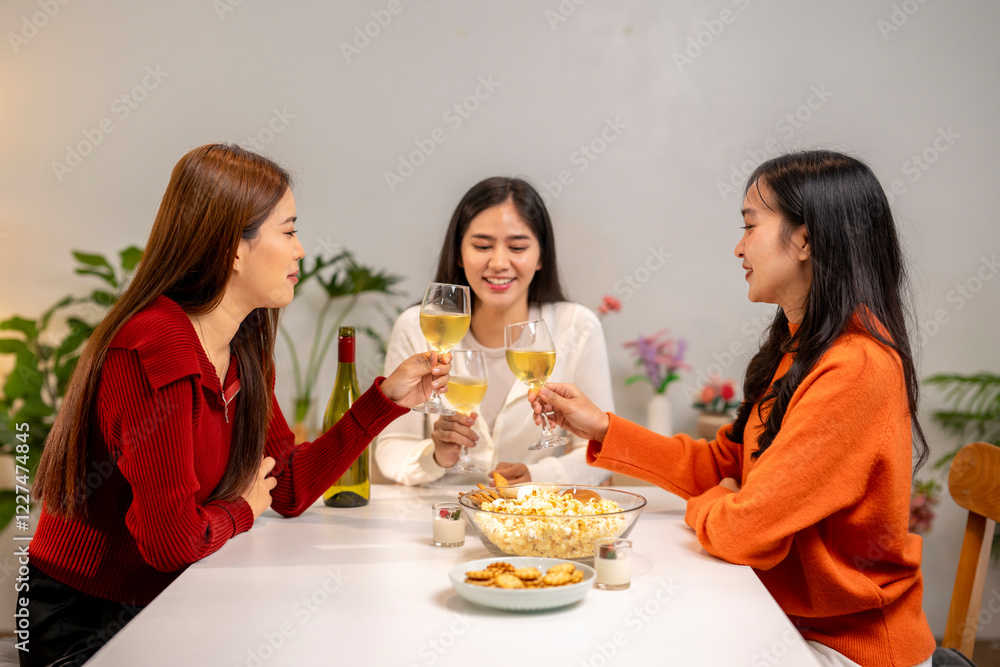 Three women are sitting at a table, each holding a wine glass and smiling Three women are sitting at a table, each holding a wine glass and smiling