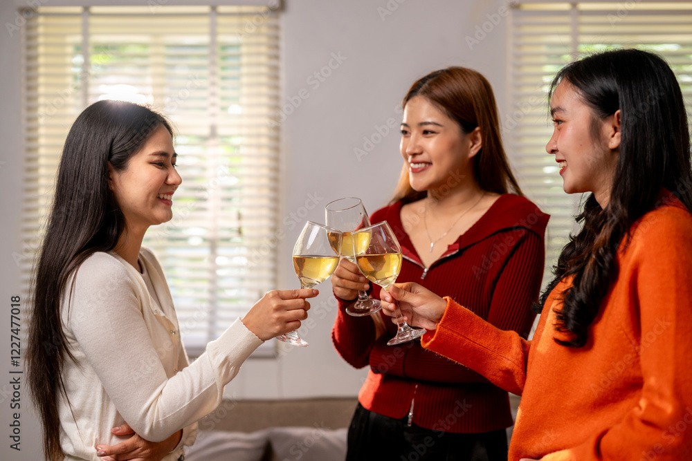 Three women are standing in a room, each holding a wine glass and smiling Three women are standing in a room, each holding a wine glass and smiling