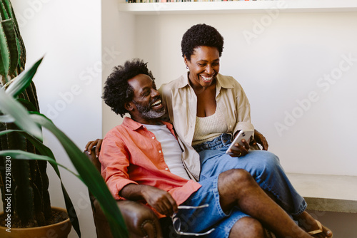 Quality time together: Happy couple sitting on the sofa, browsing a smartphone photo