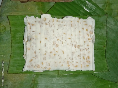 Fotografie Top view of raw tempeh wrapped in banana leaves, traditional fermented soybean food from Indonesia