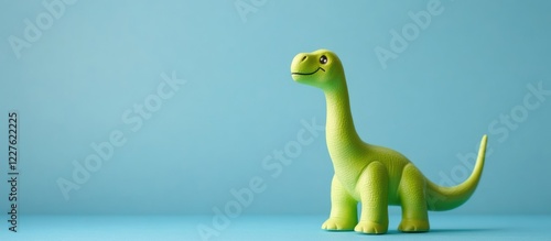 Green Toy Dinosaur Figurine Against Blue Background with Space for Text or Promotions in Kids' Products and Education Themes photo