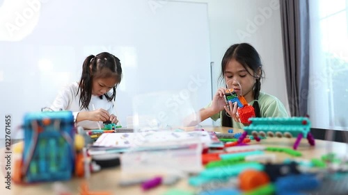 Young girls working on a robot design in Robotics programming class. STEM education using constructor blocks and laptop, Technology educational development for school kids
