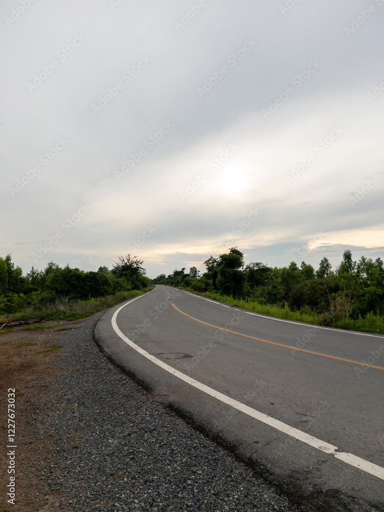 Fototapeta premium Curved Asphalt Road Along an Irrigation Canal in a Rural Landscape.