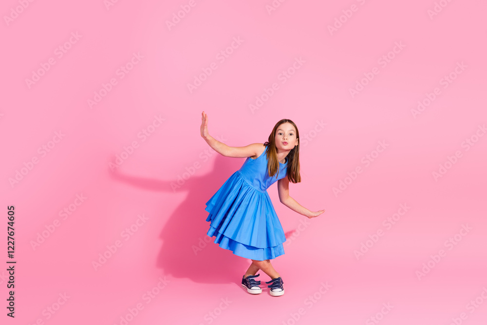 Charming young girl in a blue dress against a vibrant pink background showcasing her playful and stylish nature. Charming young girl in a blue dress against a vibrant pink background showcasing her playful and stylish nature.