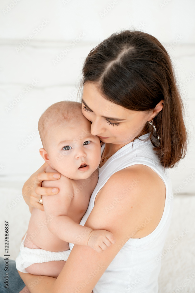 mom with a baby, an international family, a Caucasian mom with an Asian baby in her arms in the bedroom gently hugs him holding him in her arms, a place for text mom with a baby, an international family, a Caucasian mom with an Asian baby in her arms in the bedroom gently hugs him holding him in her arms, a place for text