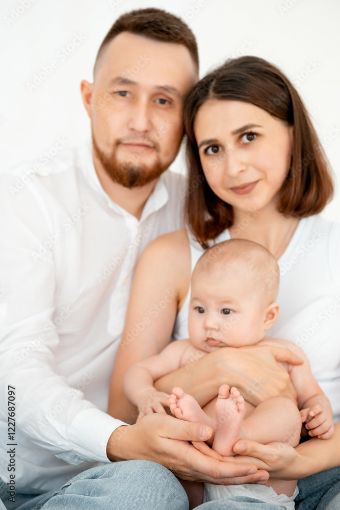 mom, dad with a baby, an international family, a Caucasian mom with an Asian husband and a baby in her arms in the bedroom gently hugs the baby holding in her arms, legs in focus mom, dad with a baby, an international family, a Caucasian mom with an Asian husband and a baby in her arms in the bedroom gently hugs the baby holding in her arms, legs in focus