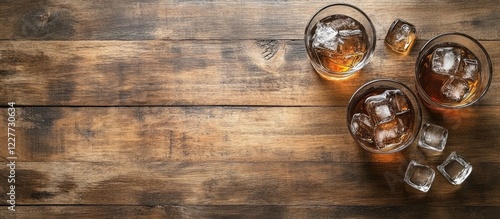 Refreshing glasses of cola with ice on rustic wooden table ideal for beverage promotional content or advertising materials photo