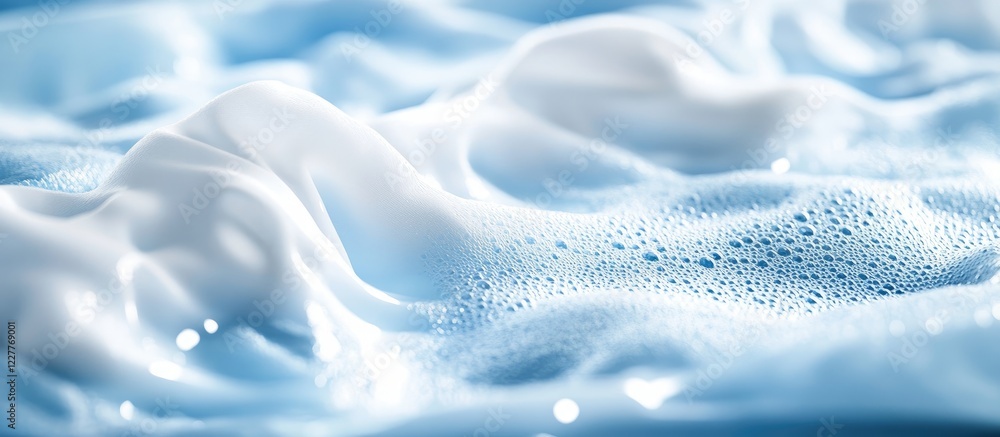 Naklejka premium Foaming liquid detergent washing white clothes in machine with soft blue bubbles and empty space for advertising or text placement
