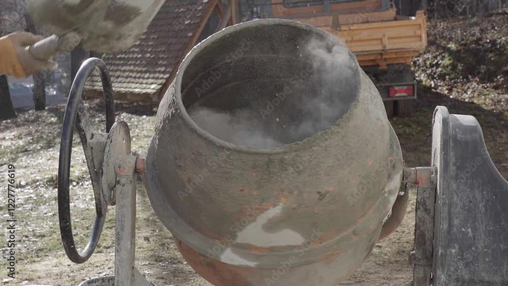 Worker is shovels concrete into the mixer. Worker is shovels concrete into the mixer.