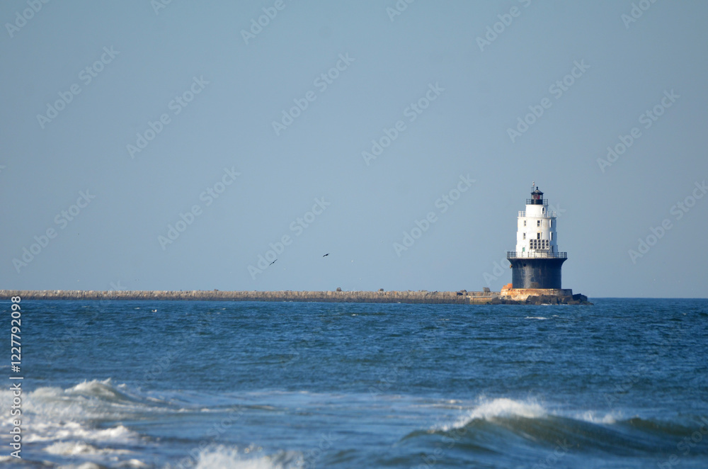 Harbor of Refuge Lighthouse in Cape Henlopen State Park with waves in foreground Harbor of Refuge Lighthouse in Cape Henlopen State Park with waves in foreground