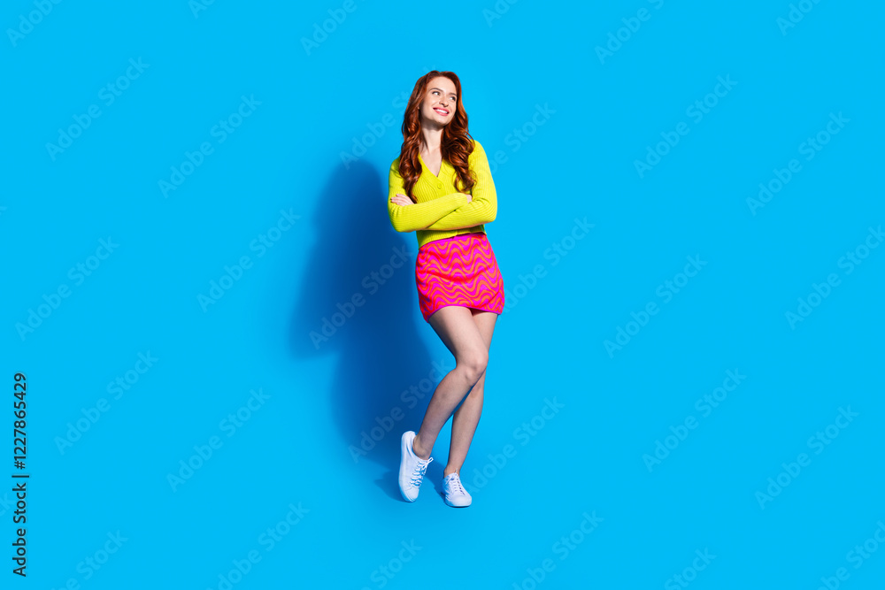 Full length photo of lovely young lady crossed hands confident look empty space dressed stylish yellow garment isolated on blue color background Full length photo of lovely young lady crossed hands confident look empty space dressed stylish yellow garment isolated on blue color background