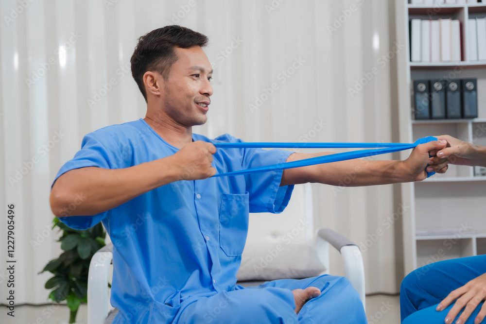 Obraz premium Physical Therapy Session: A male patient diligently participates in a physical therapy session, using a resistance band under the guidance of a therapist.